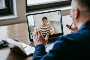 Un docente segue una lezione online con uno studente attraverso lo schermo di un portatile